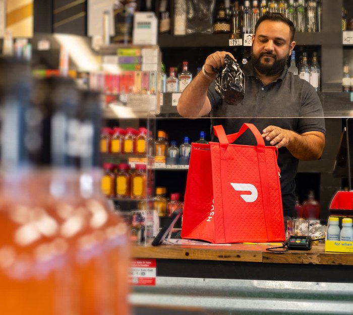 Man putting alcohol bottle in DoorDash bag